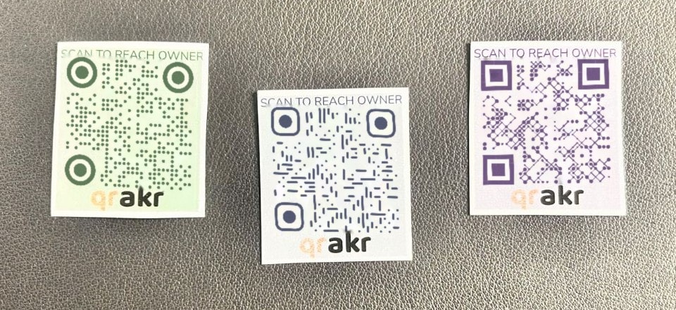 The three qrakr sticker designs, green, blue and purple, each reading Scan to reach owner